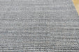 Close-up of a woven rug or textile with a heathered gray and white striped pattern, showing the texture and weave detail.
