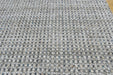 A close-up of a woven rug or mat with a textured pattern of gray, white, and black fibers.