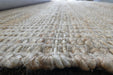 Close-up of a thick, woven natural fiber rug with a chunky braided texture in beige and cream tones.