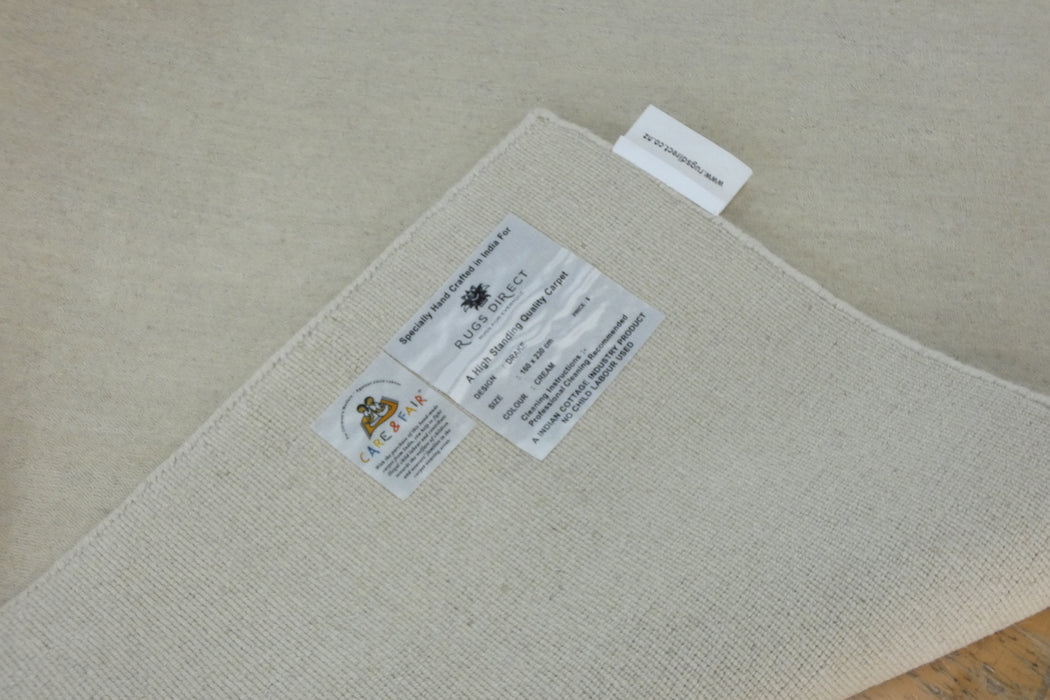 A close-up of a light beige woven fabric product, likely a rug or mat, showing a white sewn-in label and a hanging product tag. The tag reads 'BROOKFIELD HOME FURNITURE' and 'AUSTRALIA'.