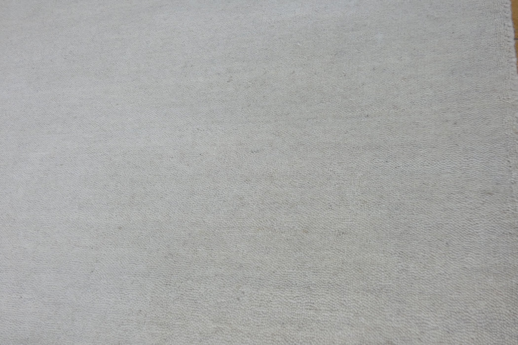 A close-up of a light beige textured fabric or material surface filling the frame.