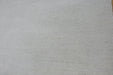 A close-up of a light beige textured fabric or material surface filling the frame.