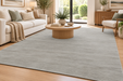 A large light gray area rug with a subtle textured pattern, styled in a bright, modern living room with a beige sofa, wooden coffee table, and light wood flooring.