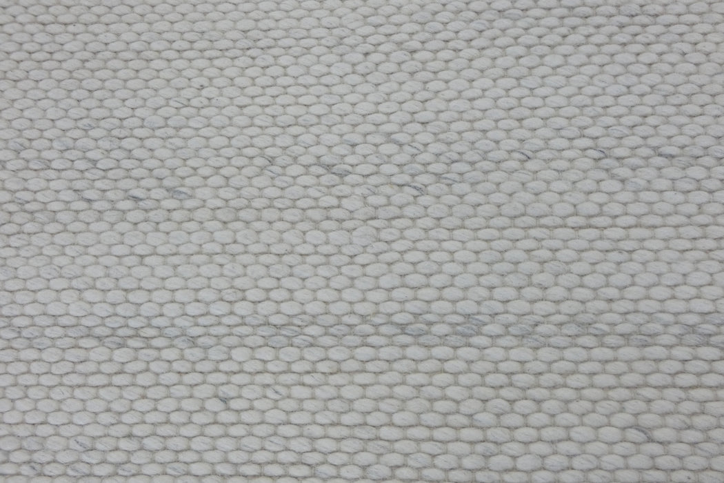 A close-up of a woven fabric texture in a light off-white or cream color with subtle gray marled threads.