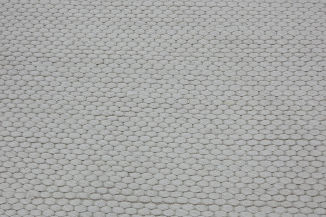 A close-up of a textured off-white woven fabric with a repeating hexagonal pattern.