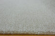 Close-up of a textured off-white or cream shag rug, showing the pile height and the frayed edge resting on a wooden floor.