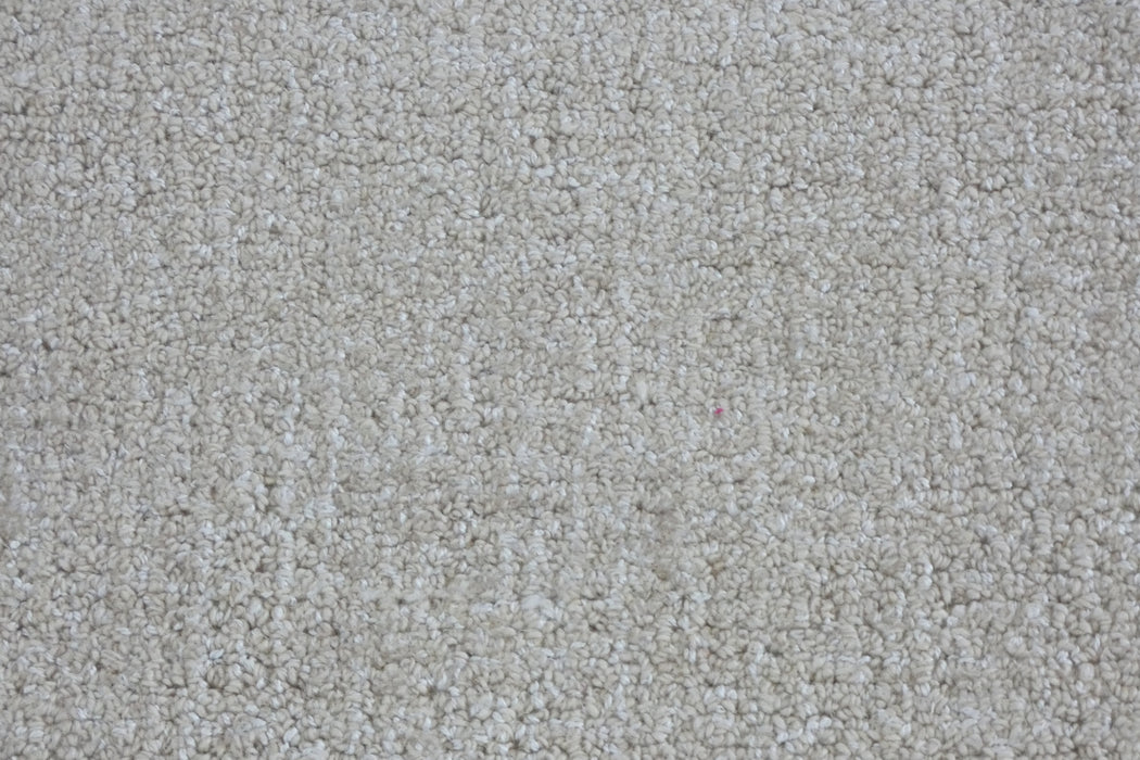 A close-up texture shot of a loop pile carpet in a warm off-white or cream color.