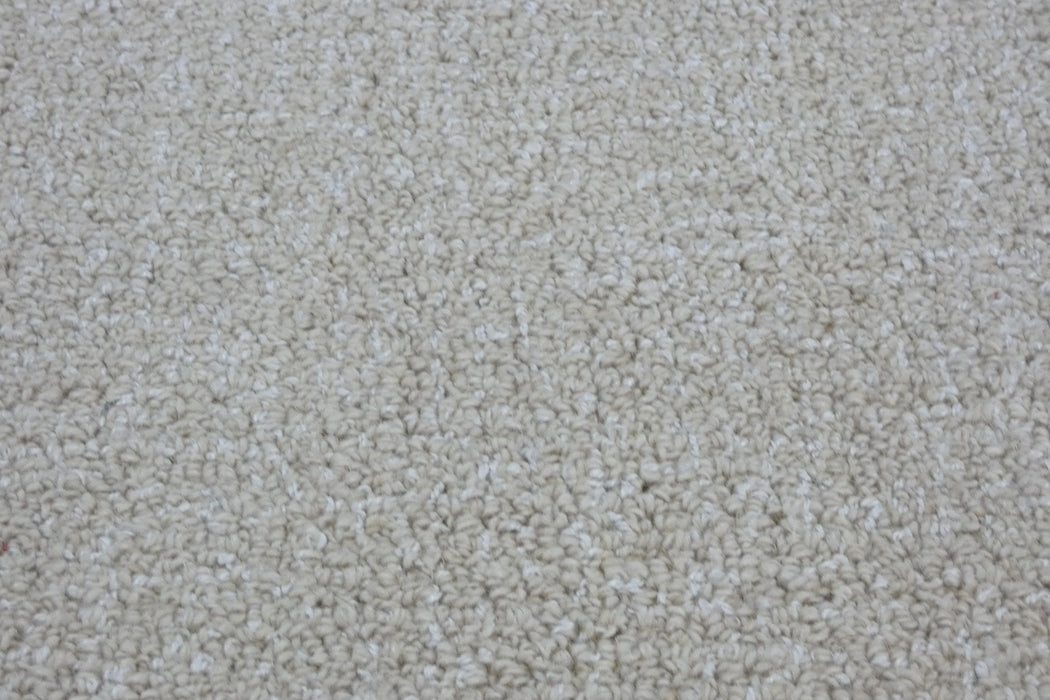 A close-up texture shot of a loop pile carpet in a warm off-white or cream color.