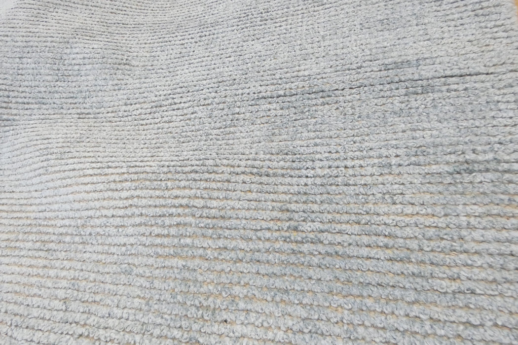 A close-up of a light gray ribbed fabric or carpet texture filling the frame.