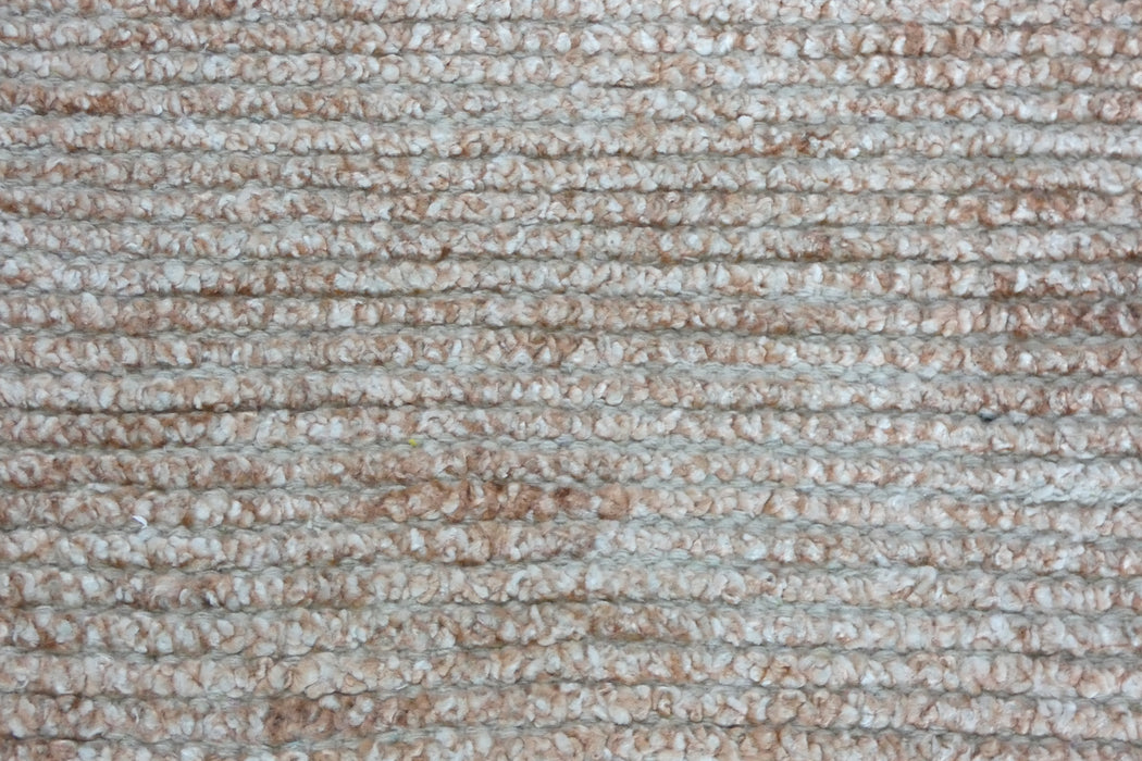A close-up texture shot of a low-pile loop-pile carpet or rug in a warm beige and off-white woven pattern.