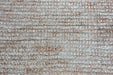 A close-up texture shot of a low-pile loop-pile carpet or rug in a warm beige and off-white woven pattern.