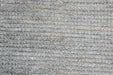 A close-up of a gray looped carpet or rug texture with horizontal ribbed rows and subtle beige gaps between the fibers.