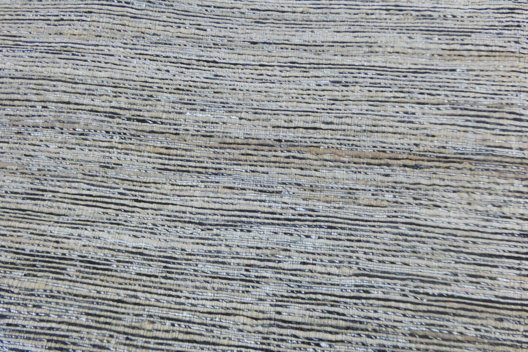 A close-up texture shot of a woven fabric or rug with horizontal stripes in gray, beige, and white.