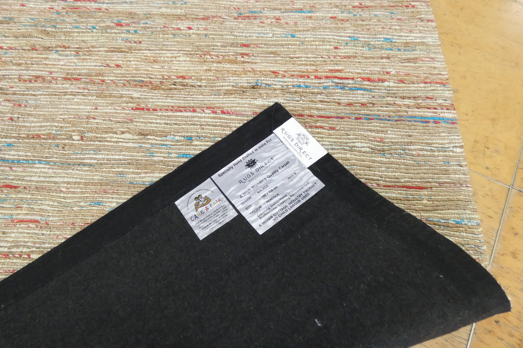A close-up of a dark charcoal gray carpet sample or rug backing laid on top of a multicolored woven rug, with two product labels visible.