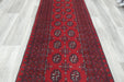 Red Afghan Turkman Bokhara hand-knotted wool hallway runner featuring repeating oval Gul medallions and traditional geometric borders. Rugs Direct NZ