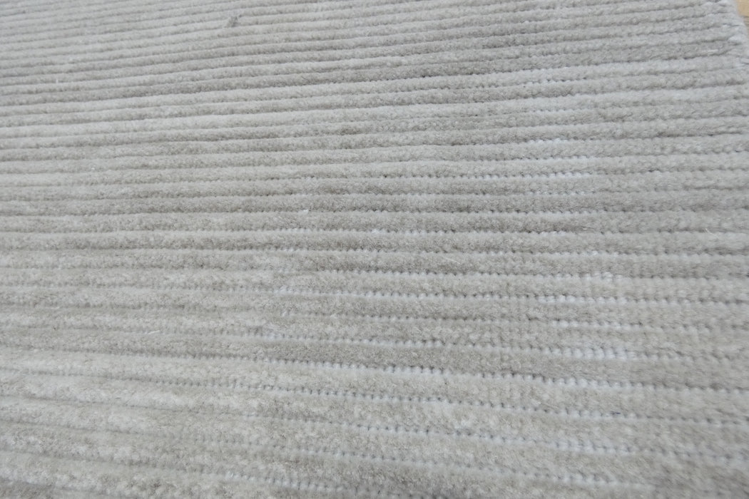 A close-up of a light gray ribbed fabric or carpet texture filling the frame.