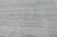A close-up of a light gray ribbed fabric or carpet texture filling the frame.