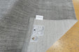 A close-up of a gray ribbed knit fabric, likely a blanket or throw, showing the underside with two labels. One label reads 'COTTON BLEACHED' and the other shows the 'COTTON CLUB' logo.