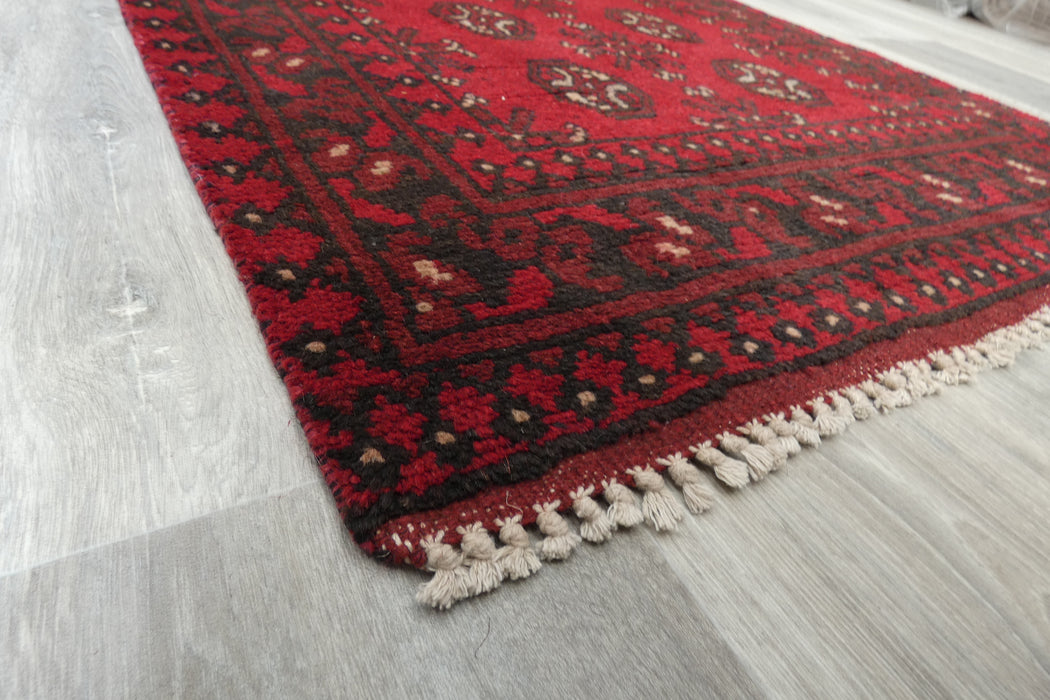 Red Afghan Turkman Bokhara hand-knotted wool hallway runner featuring repeating oval Gul medallions and traditional geometric borders.Rugs Direct NZ