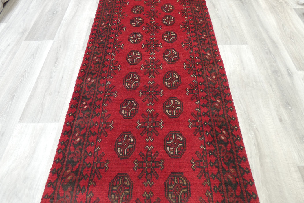 Red Afghan Turkman Bokhara hand-knotted wool hallway runner featuring repeating oval Gul medallions and traditional geometric borders.Rugs Direct NZ