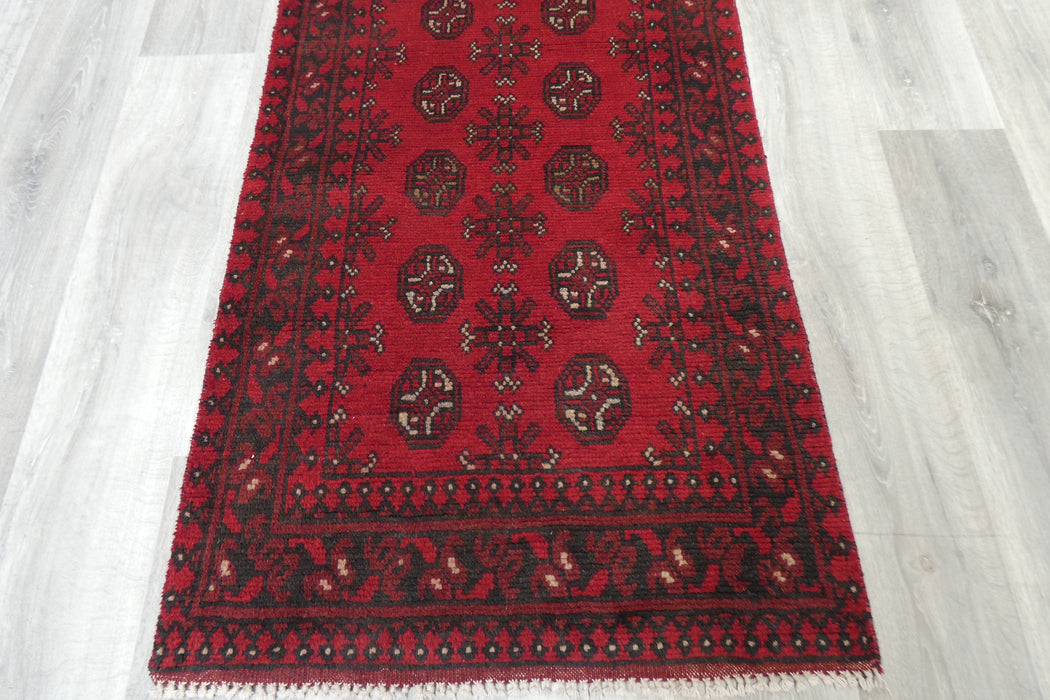 Red Afghan Turkman Bokhara hand-knotted wool hallway runner featuring repeating oval Gul medallions and traditional geometric borders.Rugs Direct NZ