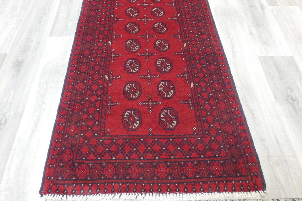Red Afghan Turkman Bokhara hand-knotted wool hallway runner featuring repeating oval Gul medallions and traditional geometric borders. Rugs Direct NZ
