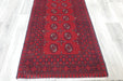 Red Afghan Turkman Bokhara hand-knotted wool hallway runner featuring repeating oval Gul medallions and traditional geometric borders. Rugs Direct NZ