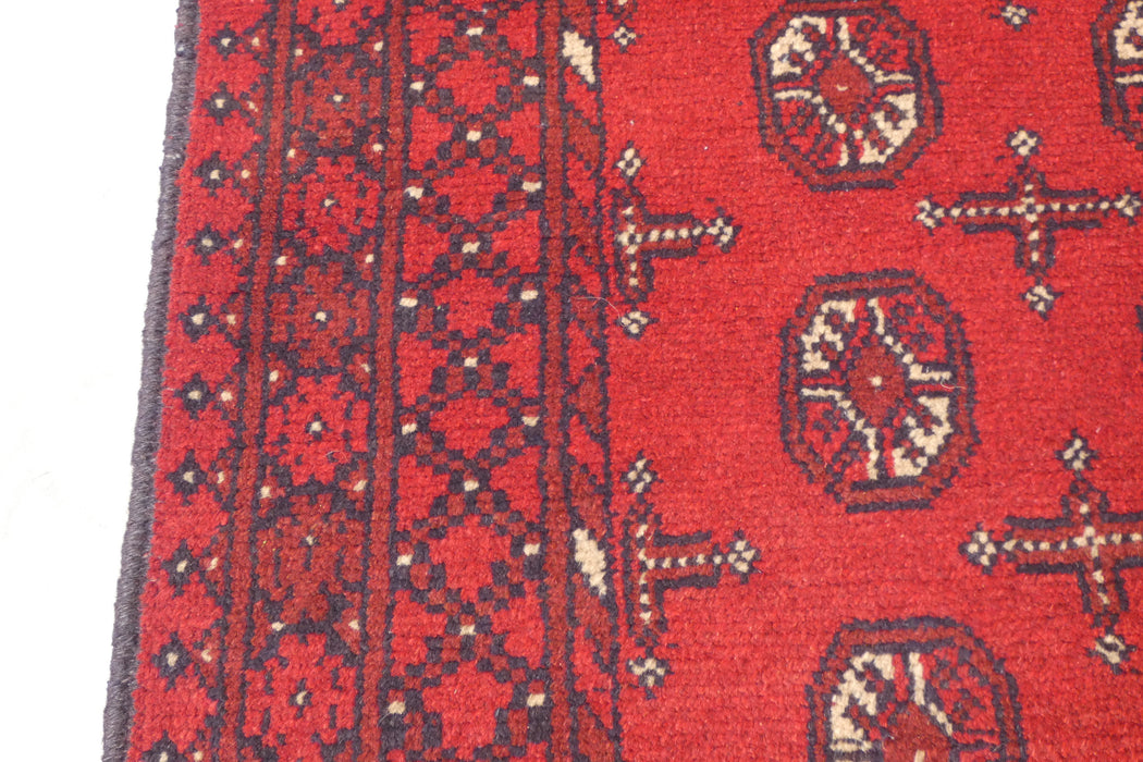Red Afghan Turkman Bokhara hand-knotted wool hallway runner featuring repeating oval Gul medallions and traditional geometric borders. Rugs Direct NZ