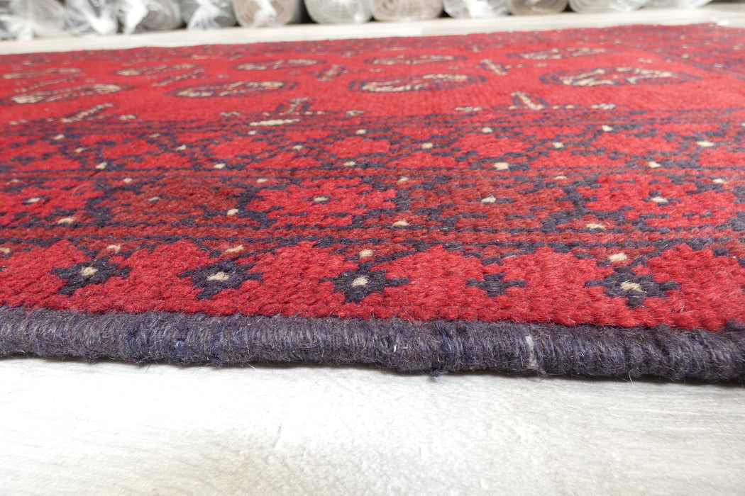 Red Afghan Turkman Bokhara hand-knotted wool hallway runner featuring repeating oval Gul medallions and traditional geometric borders. Rugs Direct NZ