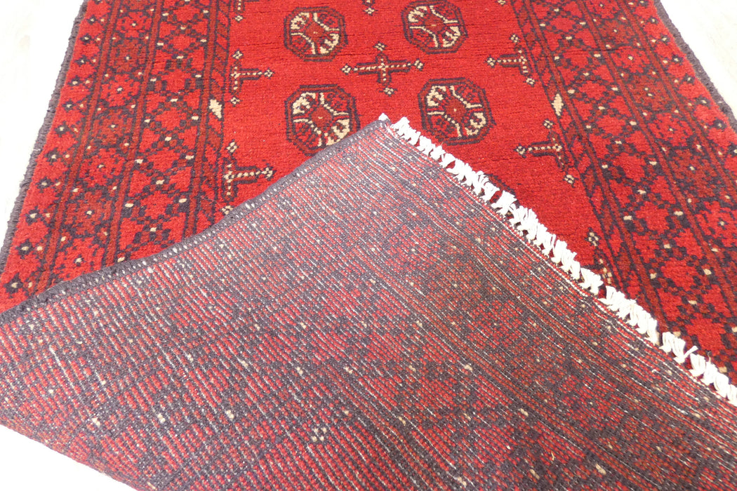 Red Afghan Turkman Bokhara hand-knotted wool hallway runner featuring repeating oval Gul medallions and traditional geometric borders. Rugs Direct NZ