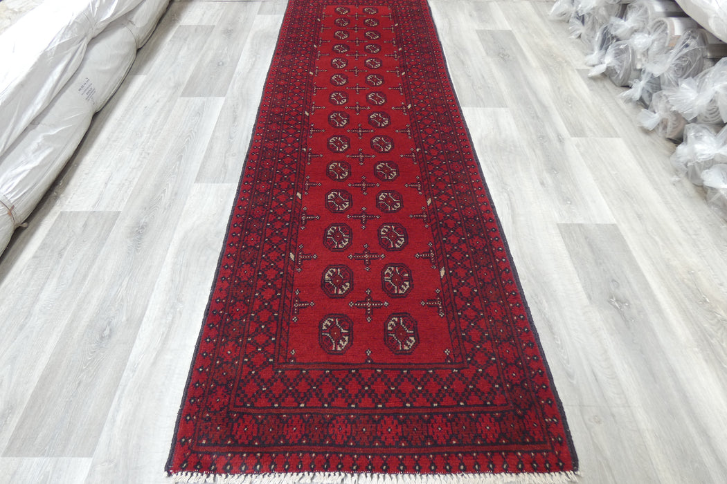 Red Afghan Turkman Bokhara hand-knotted wool hallway runner featuring repeating oval Gul medallions and traditional geometric borders. Rugs Direct NZ