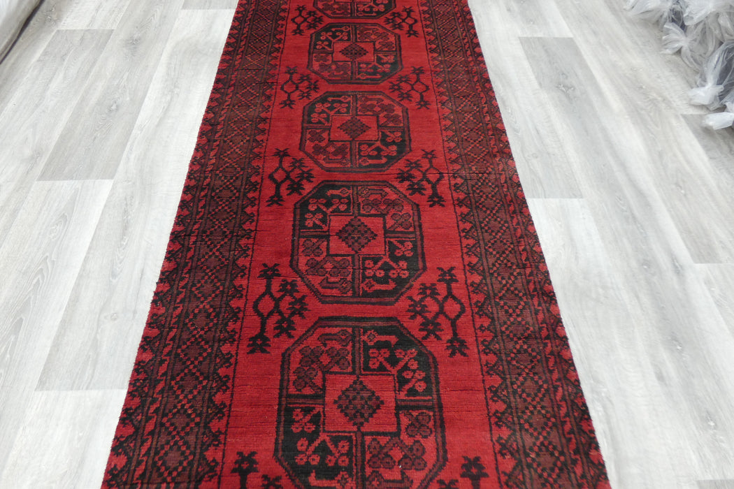 Red Afghan Turkman Bokhara hand-knotted wool hallway runner featuring repeating oval Gul medallions and traditional geometric borders.Rugs Direct NZ