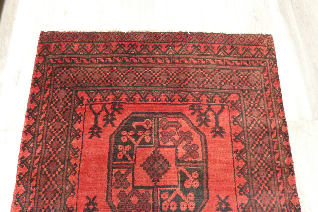Red Afghan Turkman Bokhara hand-knotted wool hallway runner featuring repeating oval Gul medallions and traditional geometric borders.Rugs Direct NZ