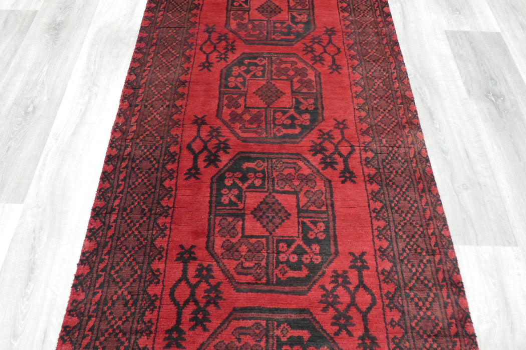 Red Afghan Turkman Bokhara hand-knotted wool hallway runner featuring repeating oval Gul medallions and traditional geometric borders.Rugs Direct NZ