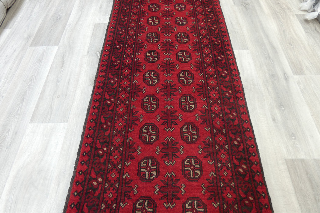 Red Afghan Turkman Bokhara hand-knotted wool hallway runner featuring repeating oval Gul medallions and traditional geometric borders.Rugs Direct NZ