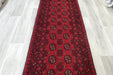 Red Afghan Turkman Bokhara hand-knotted wool hallway runner featuring repeating oval Gul medallions and traditional geometric borders.Rugs Direct NZ