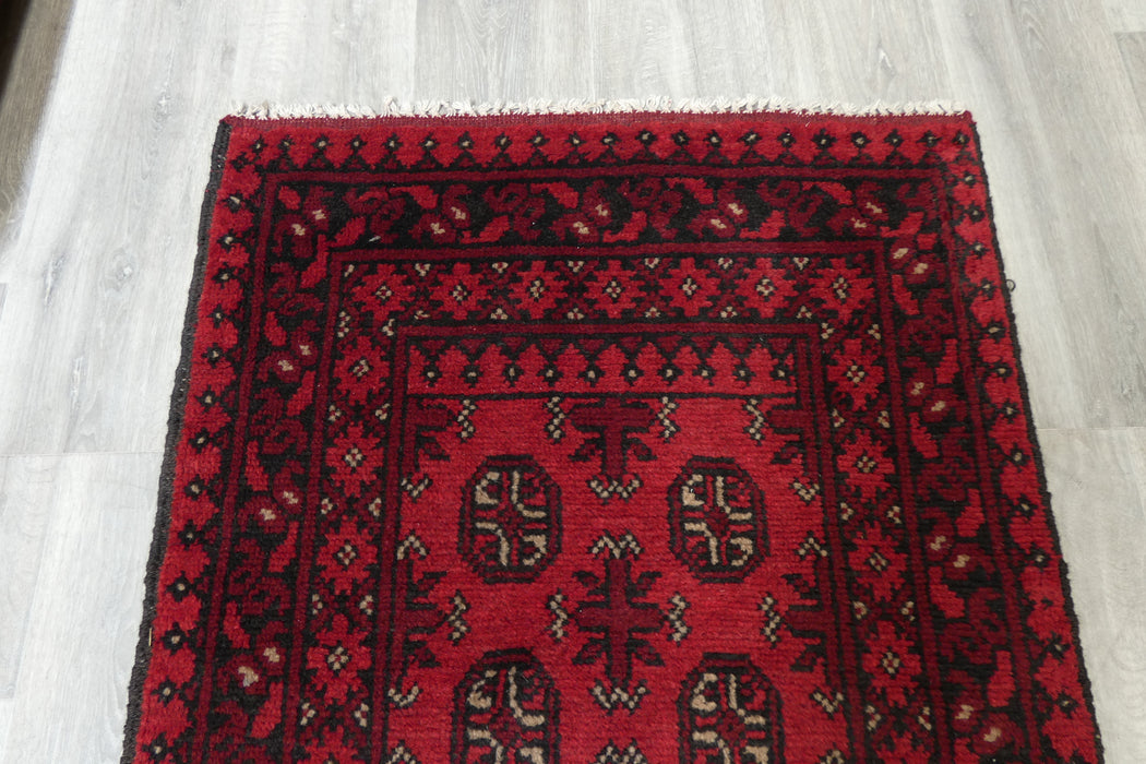 Red Afghan Turkman Bokhara hand-knotted wool hallway runner featuring repeating oval Gul medallions and traditional geometric borders.Rugs Direct NZ
