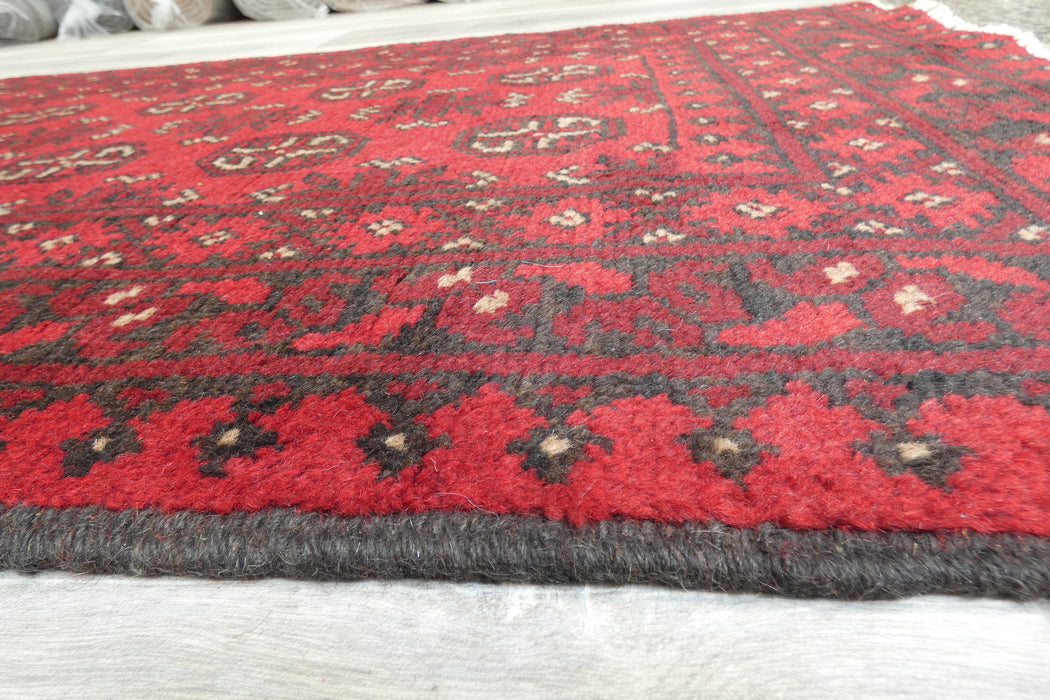 Red Afghan Turkman Bokhara hand-knotted wool hallway runner featuring repeating oval Gul medallions and traditional geometric borders.Rugs Direct NZ