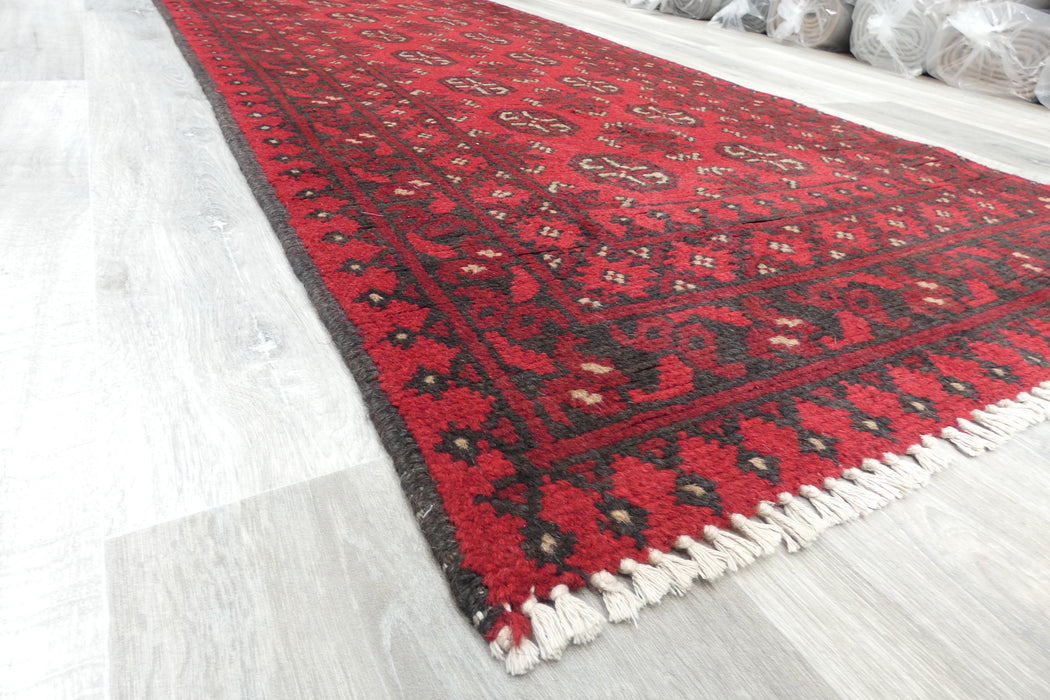 Red Afghan Turkman Bokhara hand-knotted wool hallway runner featuring repeating oval Gul medallions and traditional geometric borders.Rugs Direct NZ