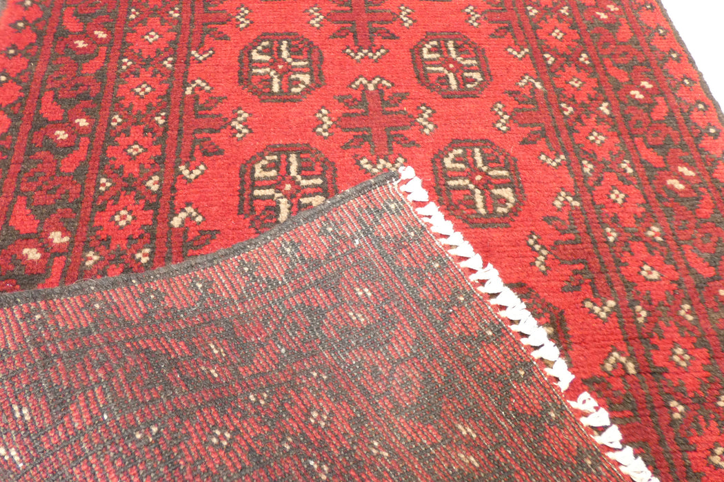 Red Afghan Turkman Bokhara hand-knotted wool hallway runner featuring repeating oval Gul medallions and traditional geometric borders.Rugs Direct NZ