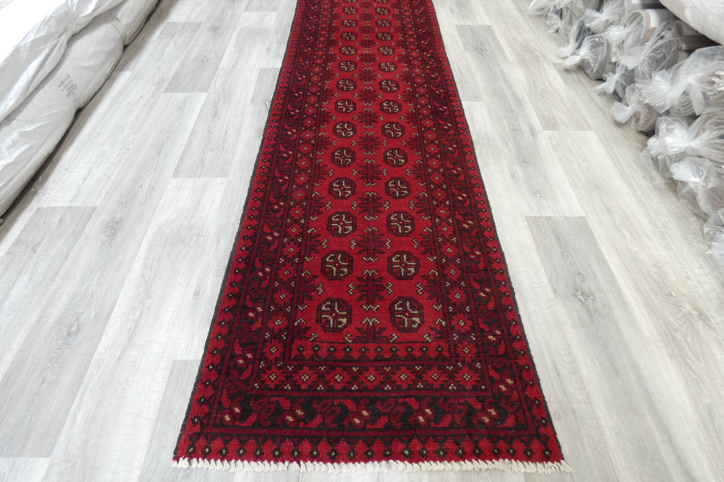 Red Afghan Turkman Bokhara hand-knotted wool hallway runner featuring repeating oval Gul medallions and traditional geometric borders.Rugs Direct NZ