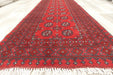 Red Afghan Turkman Bokhara hand-knotted wool hallway runner featuring repeating oval Gul medallions and traditional geometric borders. Rugs Direct NZ