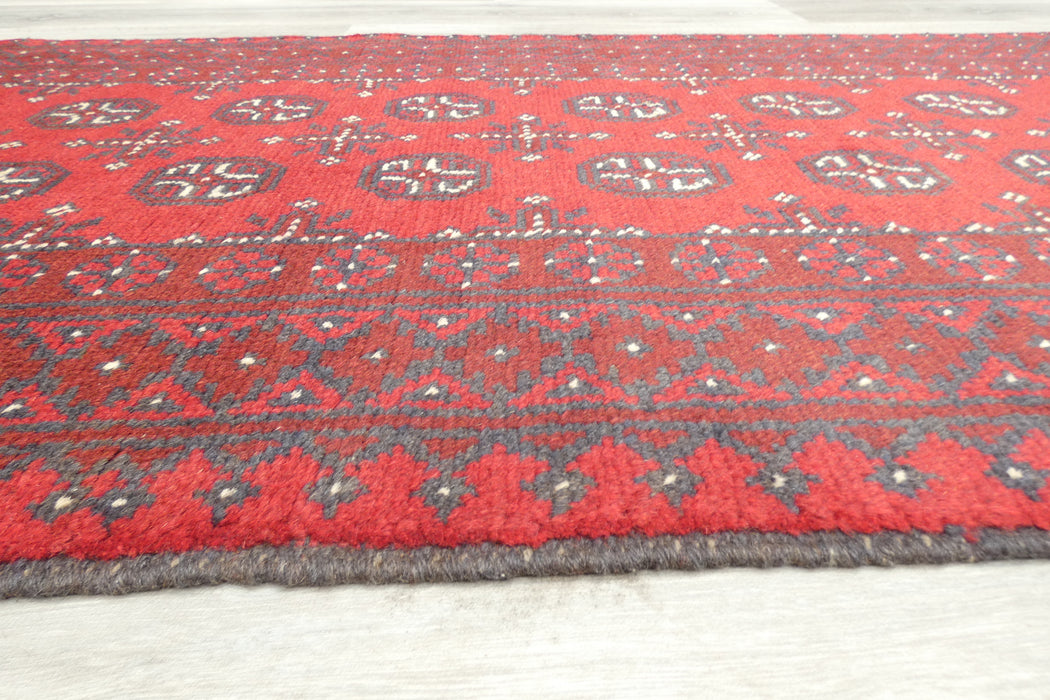Red Afghan Turkman Bokhara hand-knotted wool hallway runner featuring repeating oval Gul medallions and traditional geometric borders. Rugs Direct NZ