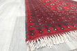 Red Afghan Turkman Bokhara hand-knotted wool hallway runner featuring repeating oval Gul medallions and traditional geometric borders. Rugs Direct NZ