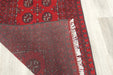 Red Afghan Turkman Bokhara hand-knotted wool hallway runner featuring repeating oval Gul medallions and traditional geometric borders. Rugs Direct NZ